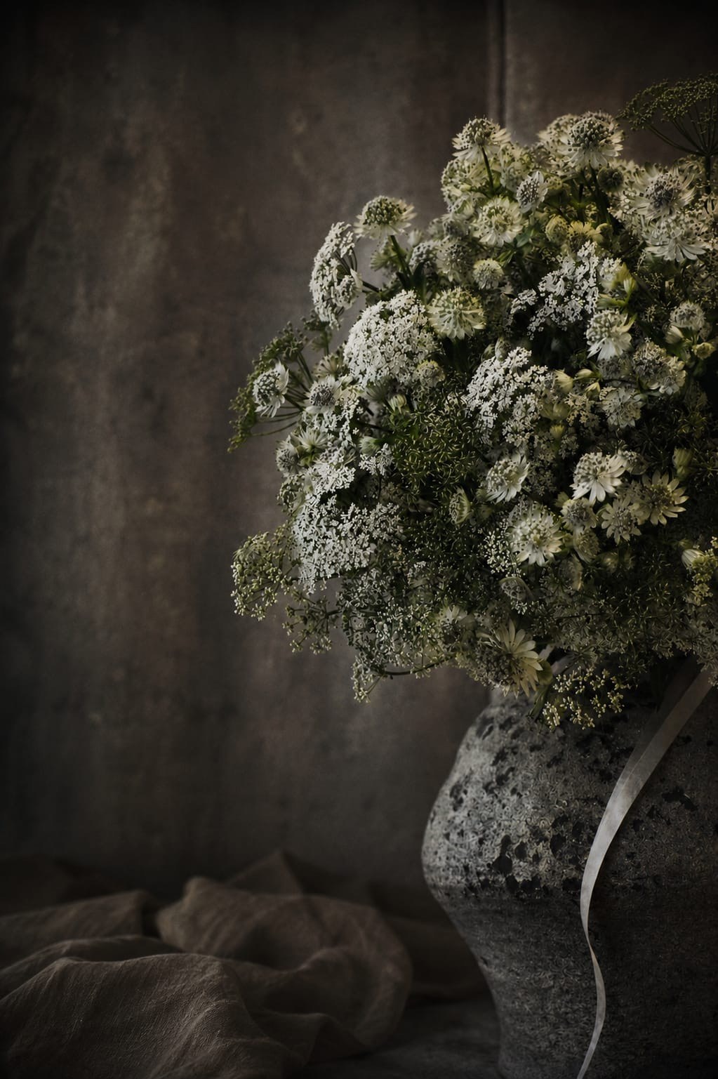 Feiner weißer Blumenstrauß in einer dunklen Vase – florale Raumgestaltung